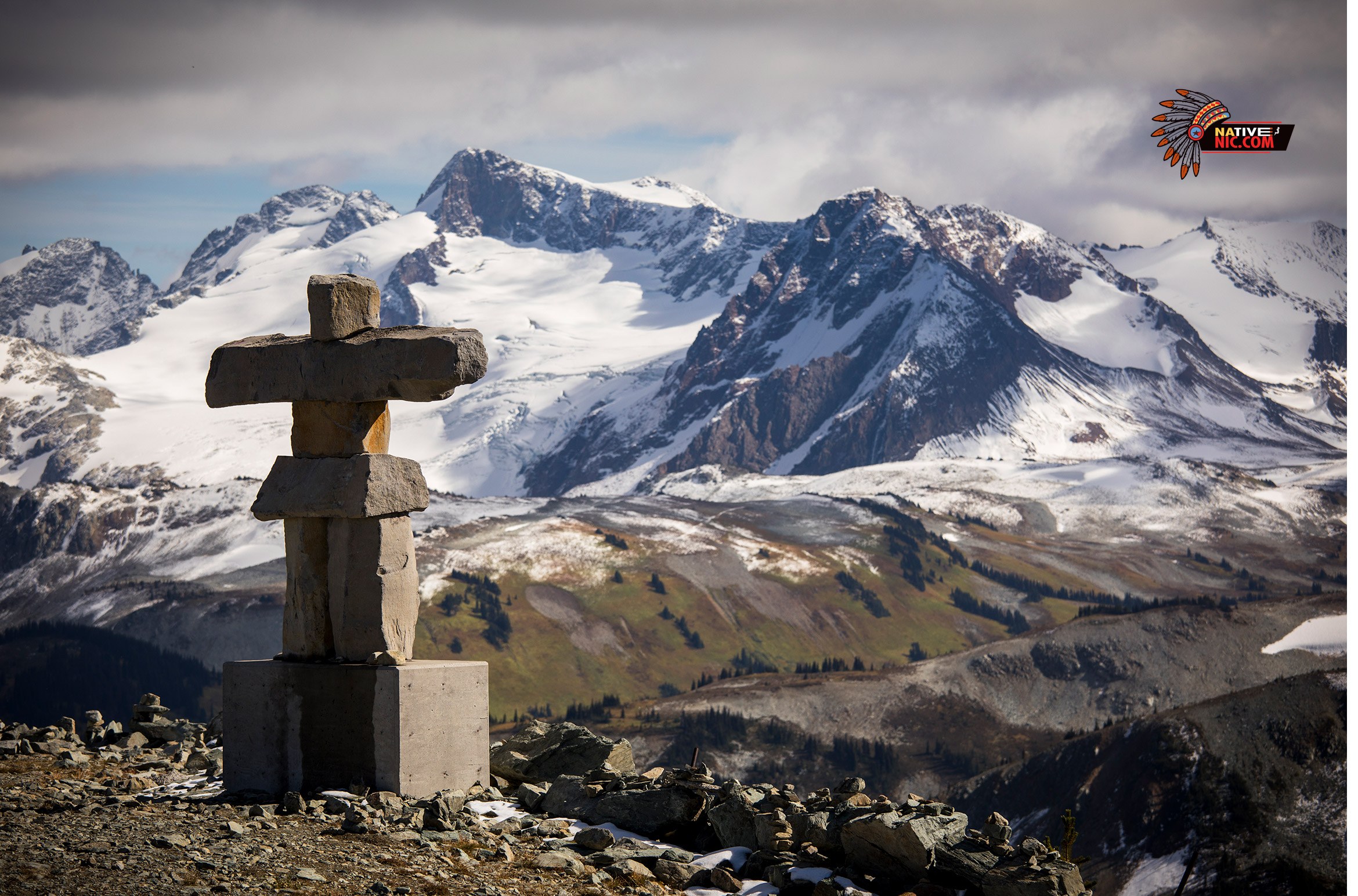 Inuksuk – traditional Canadian Indigenous landmark with snow-capped mountains